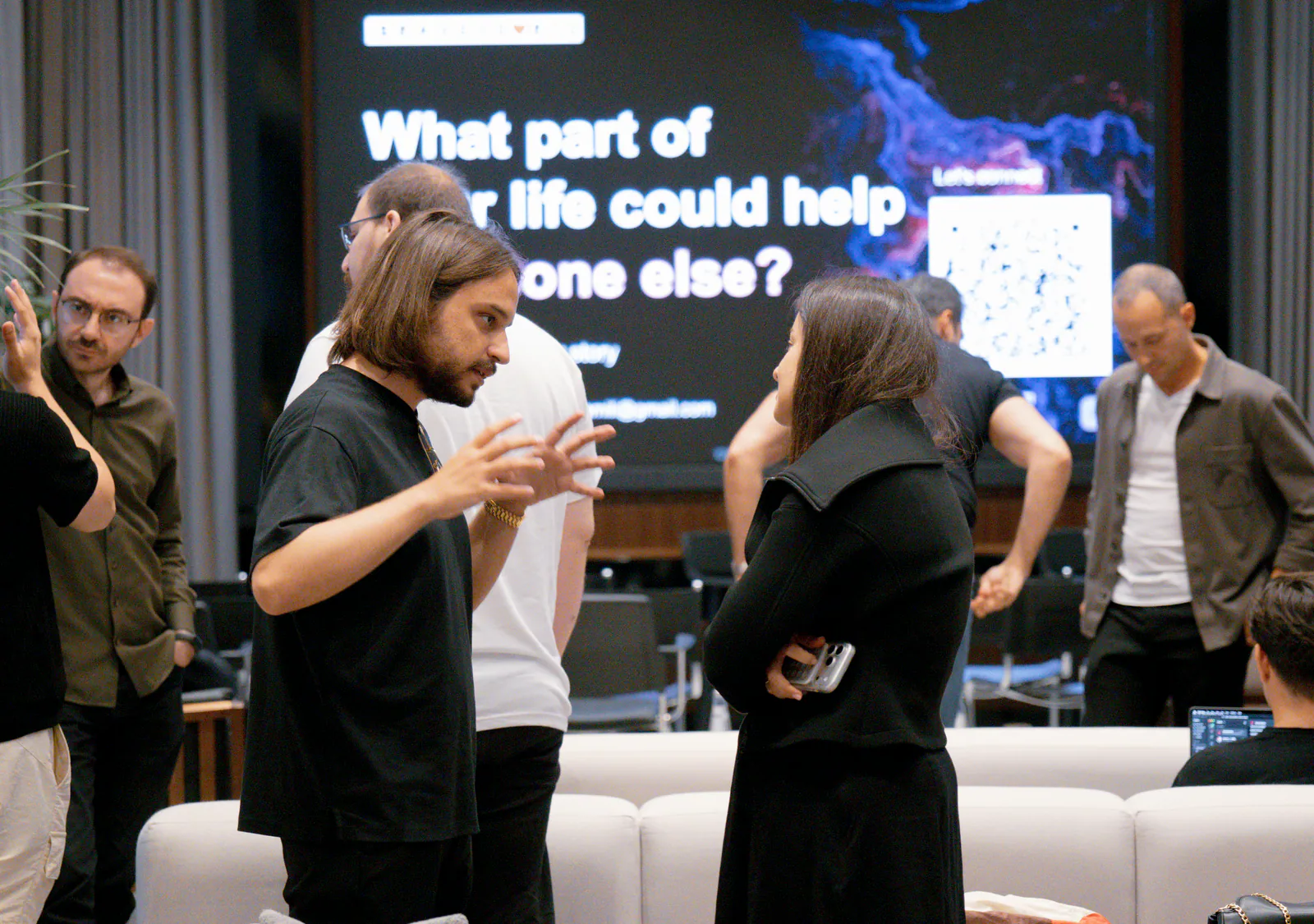 Participants chatting in front of a large screen during a hackathon