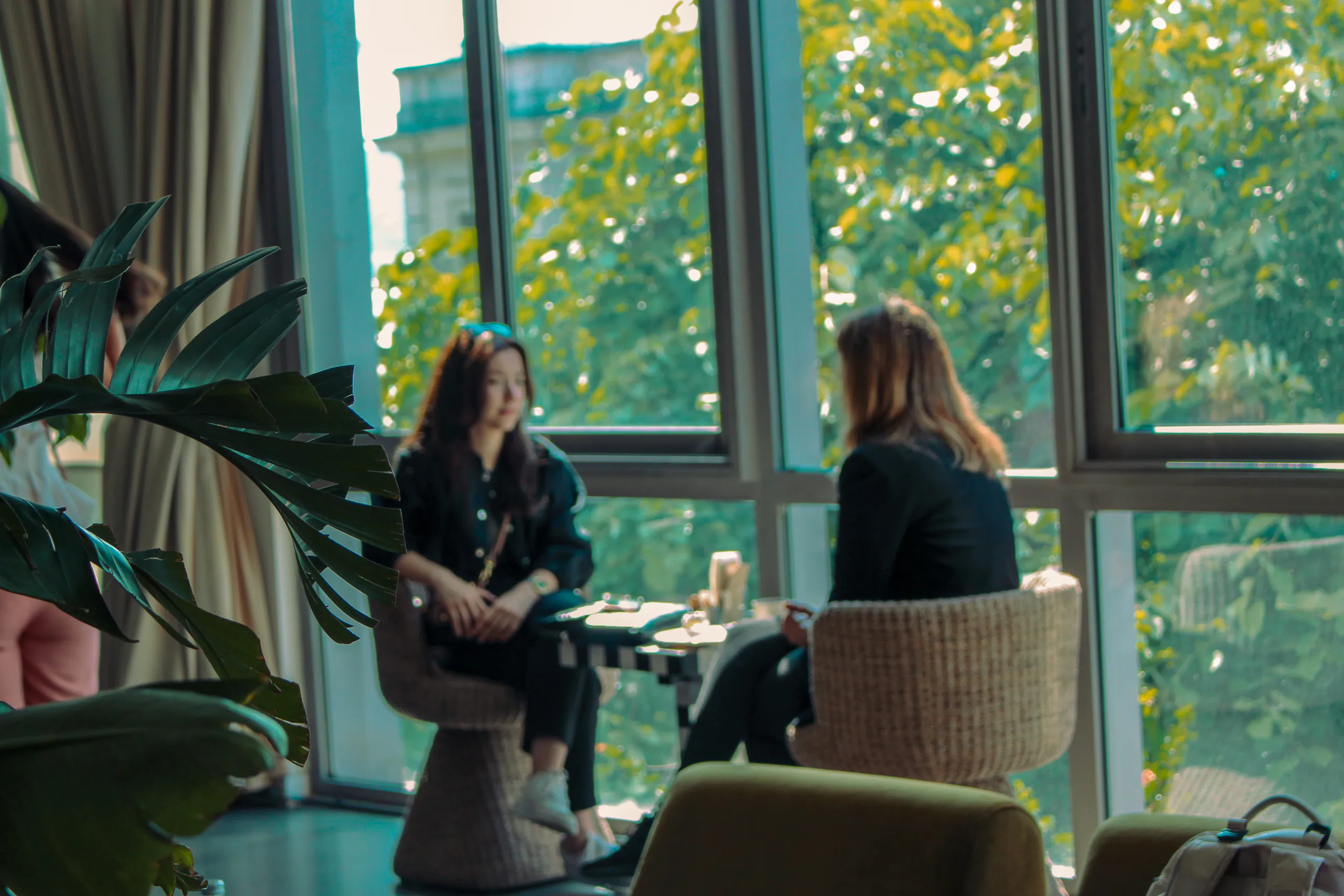 Two people chatting face to face in wicker armchairs in front of large windows