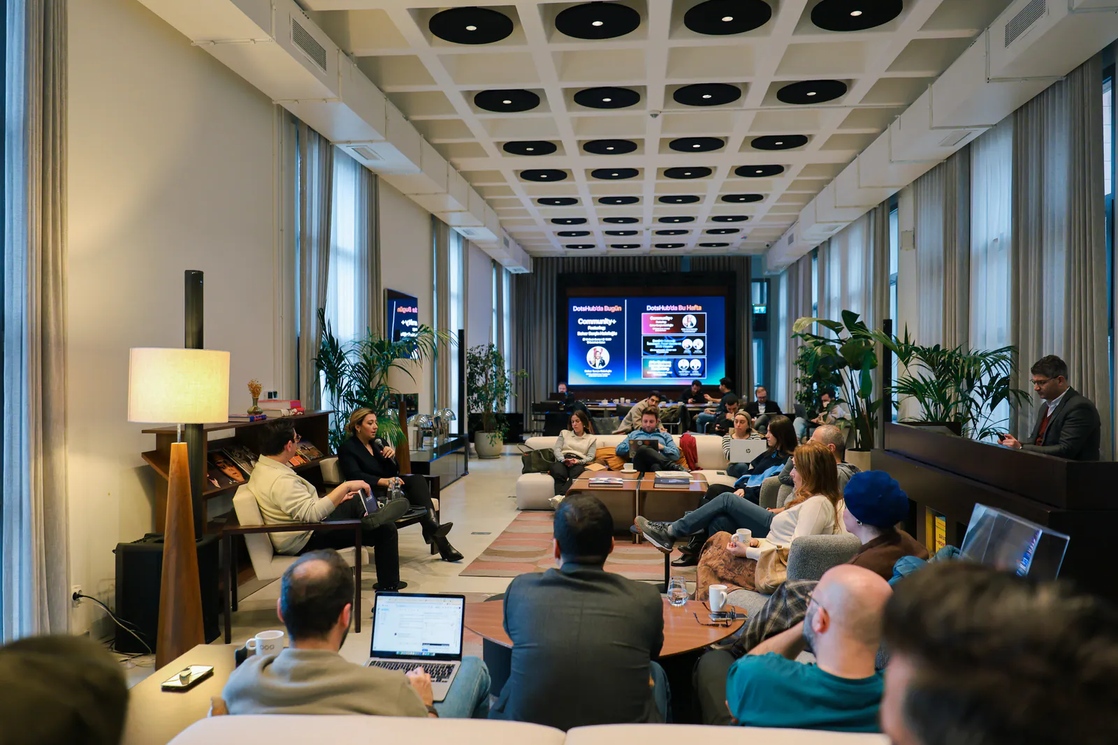 DotsHub salonunda ekrandaki sunumu izleyen kalabalık bir topluluk